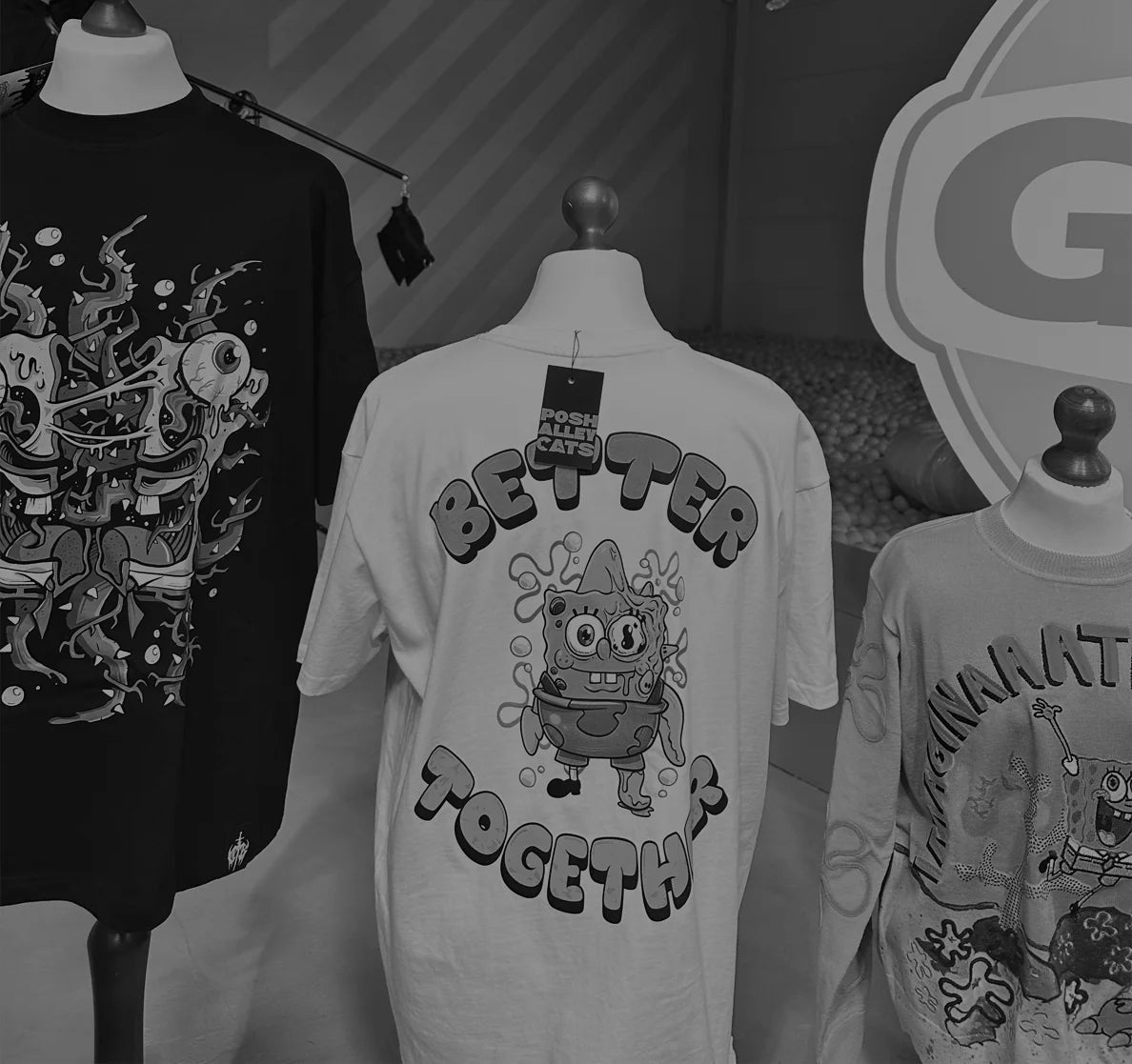 T-shirts with graphic designs on mannequins against a dark background