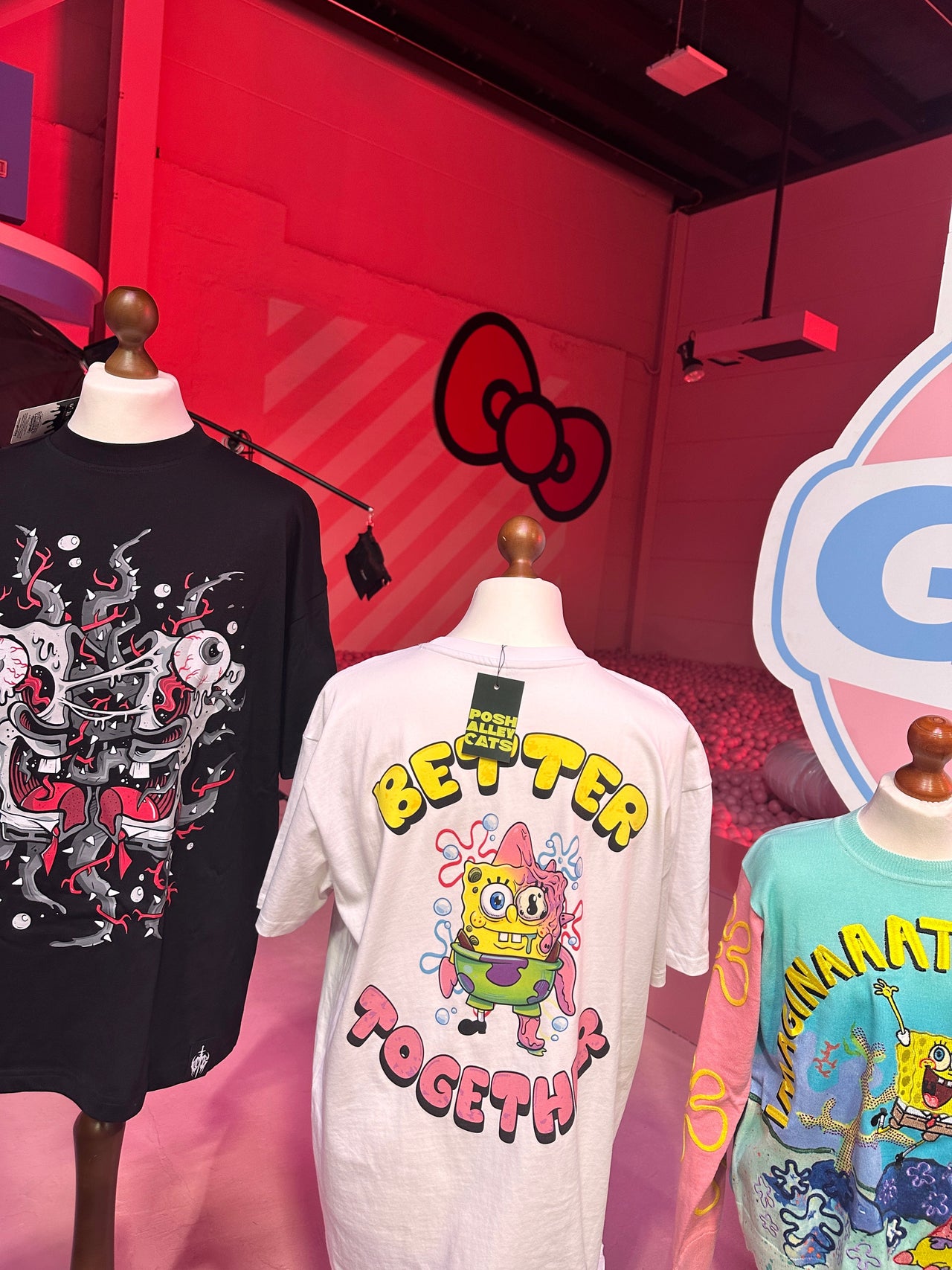 Three mannequins wearing colorful t-shirts with cartoon characters against a red background.